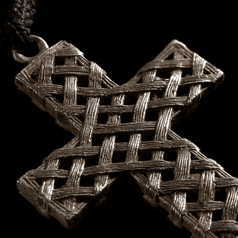 Extreme macro close-up of a Lalibela Ethiopian cross pendant showing the intricate interwoven diamond lattice pattern, individual silver wire crossings and natural patina visible against a black background