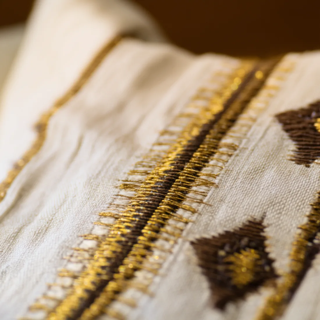 Close-up of a gold tibeb border woven into a white habesha kemis
